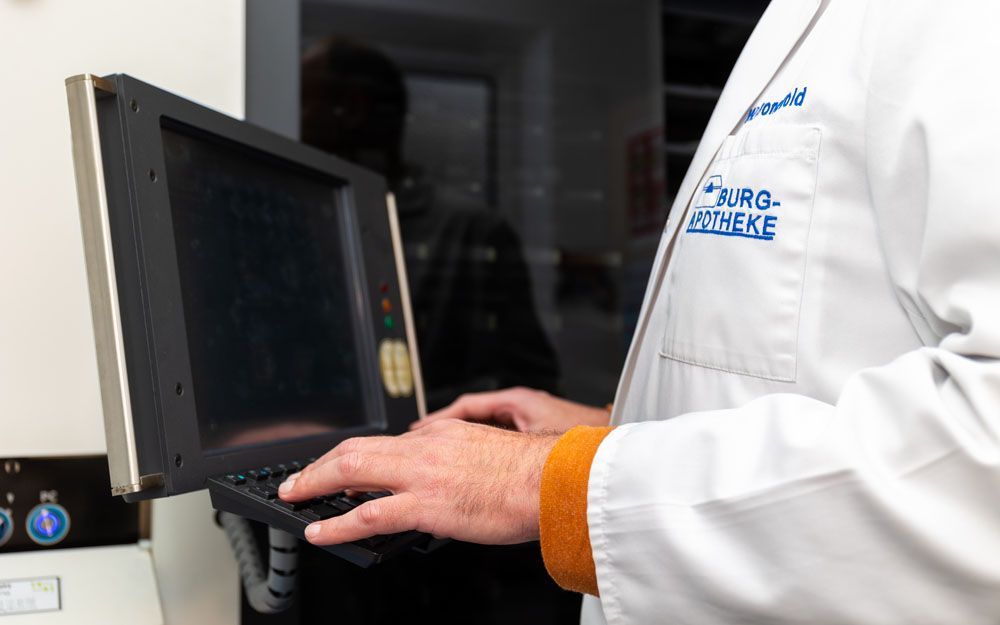 Ein Mann im Laborkittel tippt auf einem Laptop.