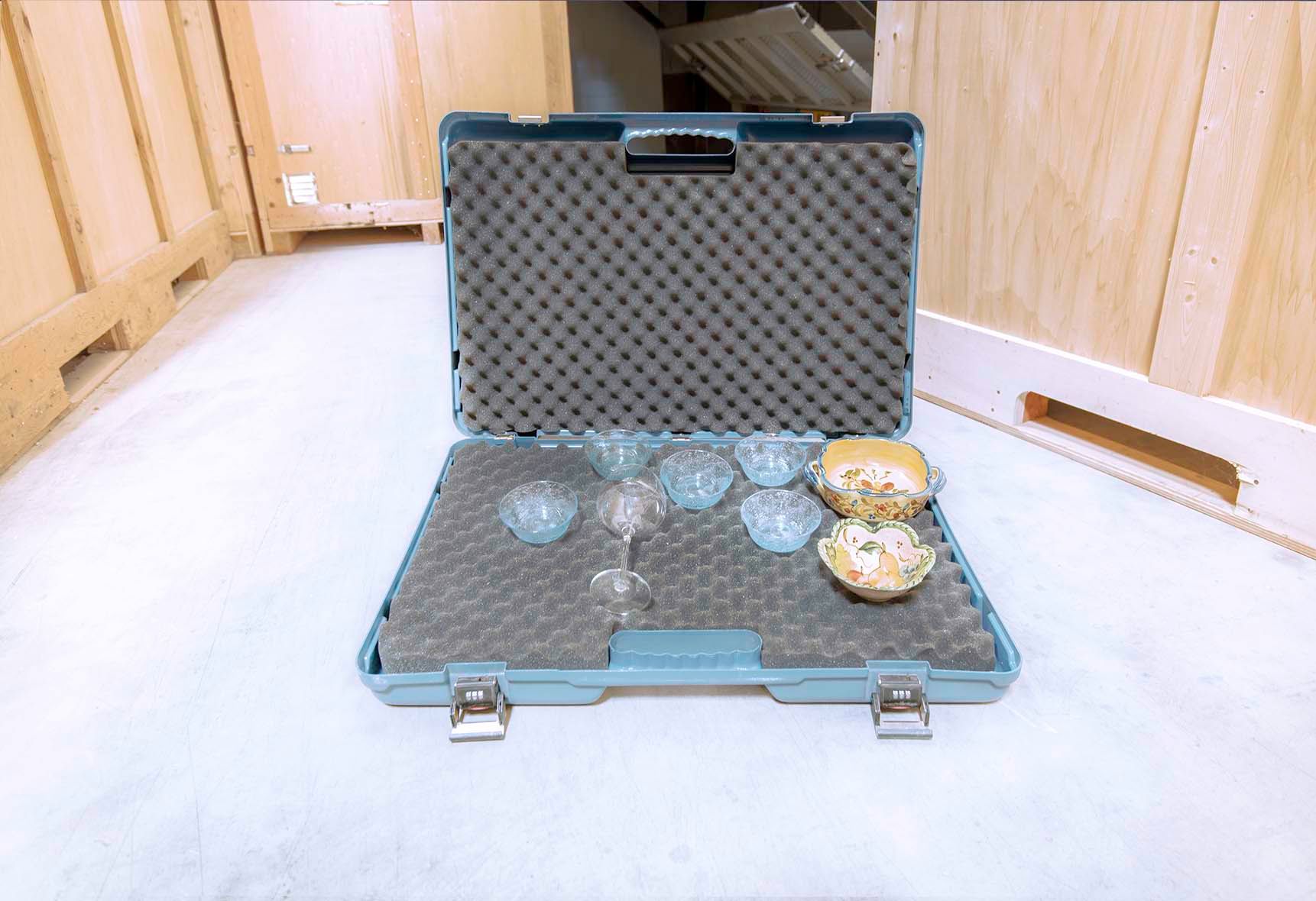 Coffret ouvert, rembourré de mousse, contenant de la verrerie et une petite théière.