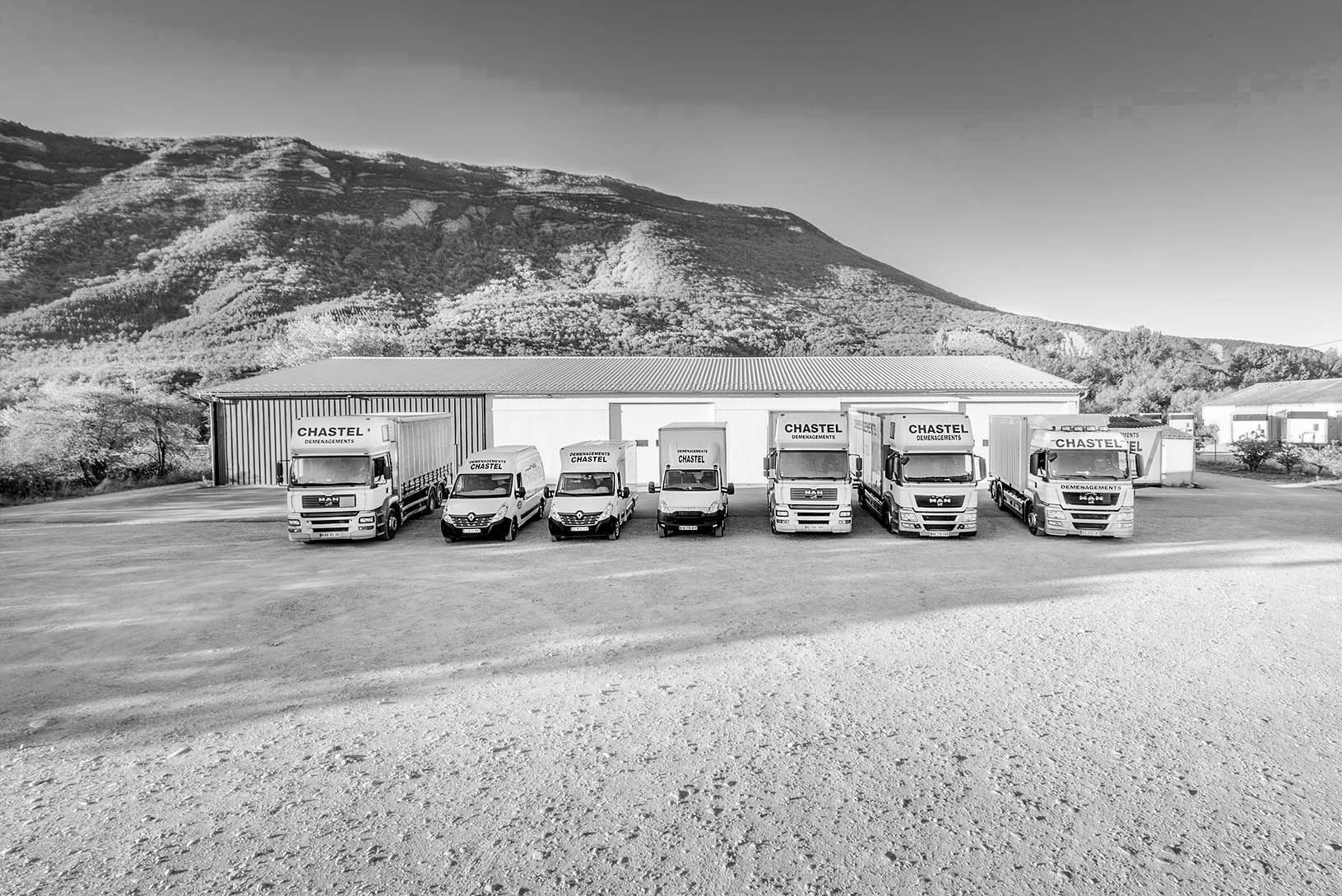 Sept camions stationnés devant un entrepôt de déménagement.