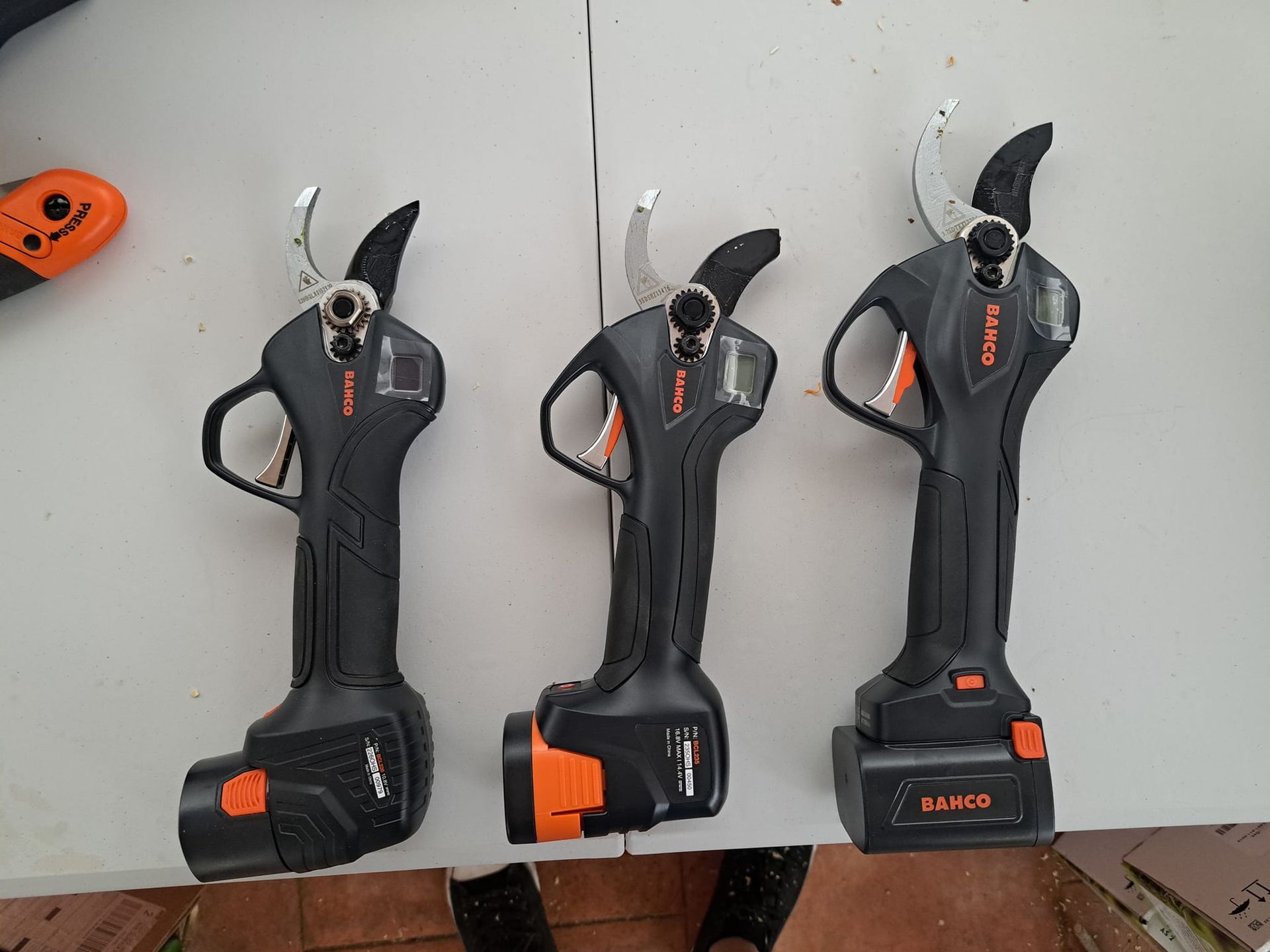 Tres tijeras de podar inalámbricas están sobre una mesa.