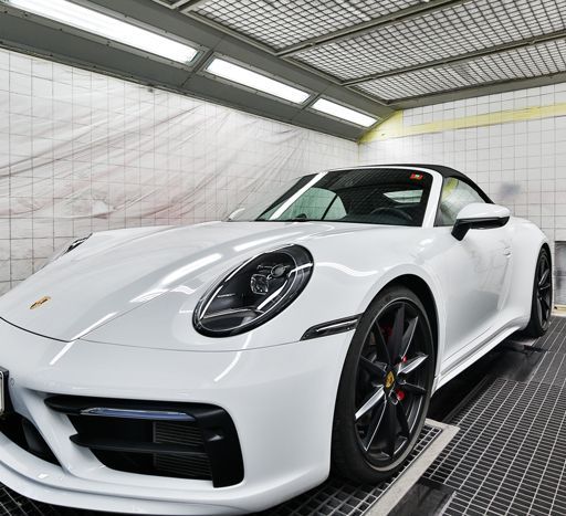 Ein weißer Porsche 911 steht in einer Garage.