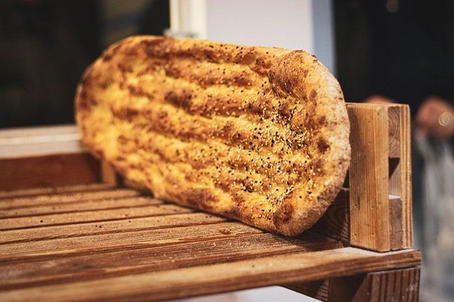 Ein Laib Brot liegt auf einem Holzregal.
