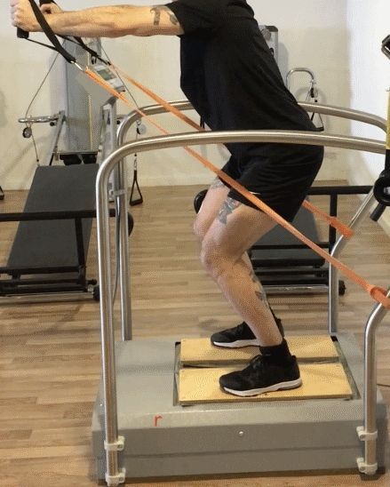 Persona che esegue un esercizio di squat con fasce elastiche in palestra.