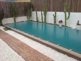 Una gran piscina rodeada de cactus y grava.