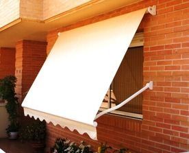 Un toldo blanco cuelga sobre una ventana de un edificio de ladrillo.