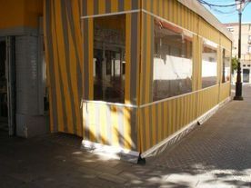 Un toldo de rayas amarillas y grises está en el costado de un edificio.