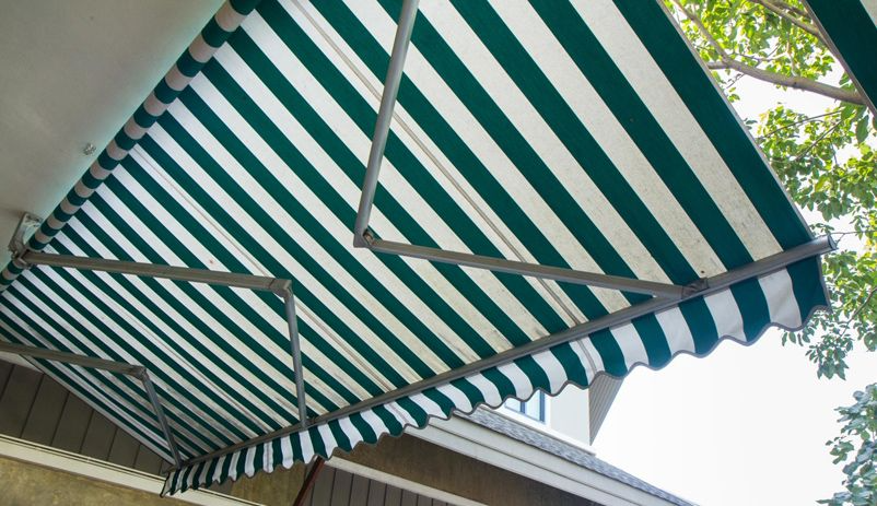 Un toldo de rayas verdes y blancas está en el costado de un edificio.
