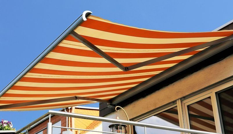 Un toldo de rayas naranjas y amarillas está en un balcón.