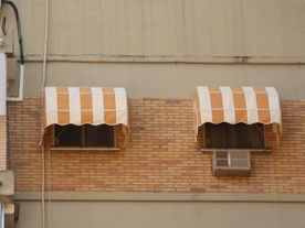 Hay dos toldos en el costado de un edificio de ladrillo.