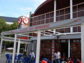 Un grupo de personas están sentadas afuera de un restaurante llamado San Bernardo.