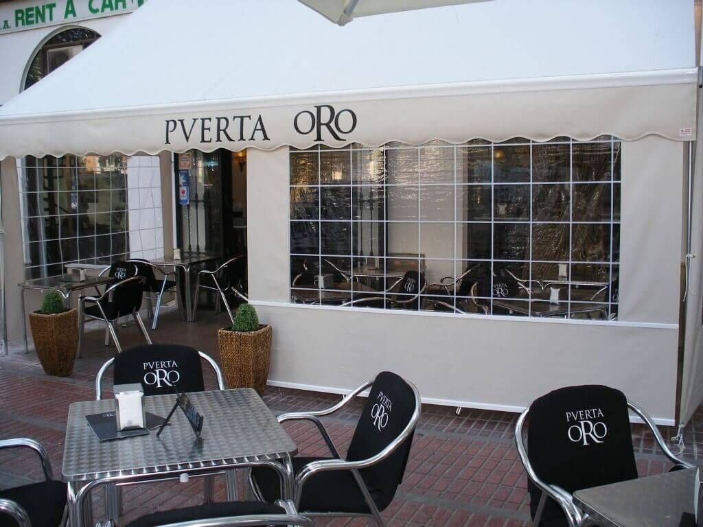 Mesas y sillas afuera de un restaurante llamado pverta oro