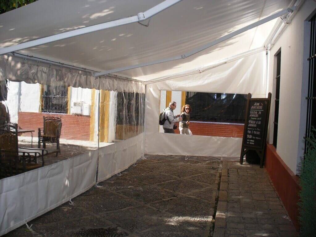 Un hombre parado debajo de una tienda de campaña con un cartel que dice 'abierto'.