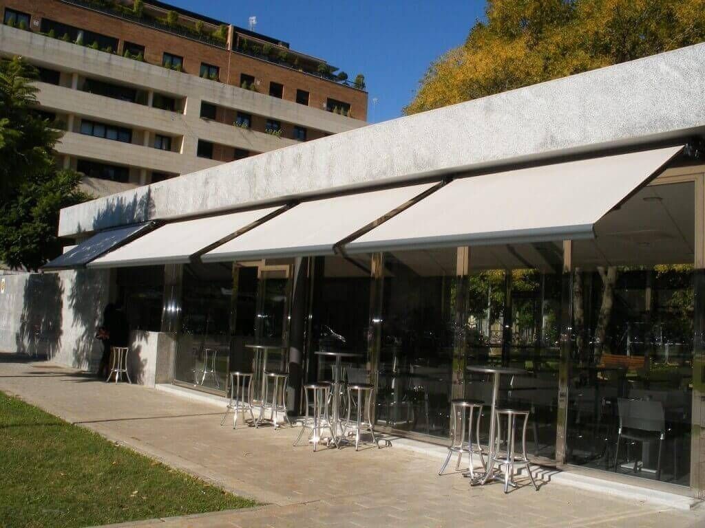 Un edificio con mesas y sillas bajo un toldo.