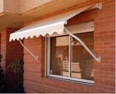 Un toldo blanco cuelga sobre una ventana de un edificio de ladrillo.