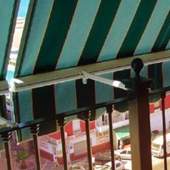 Un balcón con un toldo de rayas verdes y blancas encima.