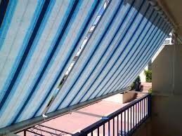 Un toldo de rayas azules y blancas está en un balcón.