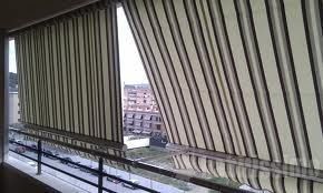 Un balcón con un toldo de rayas y vista a una ciudad.