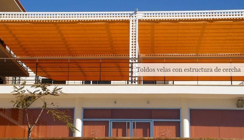 Un edificio con un cartel que dice toldos velas.