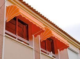 Un edificio con toldos naranjas en las ventanas y balcones.