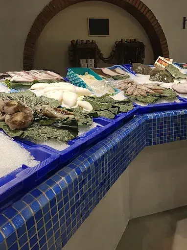 Un mostrador lleno de bandejas de pescado y verduras en hielo.