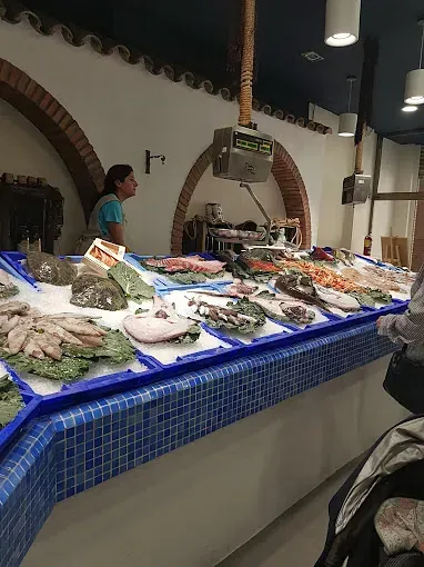 Una mujer está parada detrás de un mostrador lleno de mariscos.