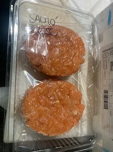 Hay dos hamburguesas en un recipiente de plástico.