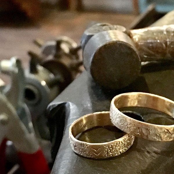 Dos anillos de oro están sobre una mesa junto a un martillo.