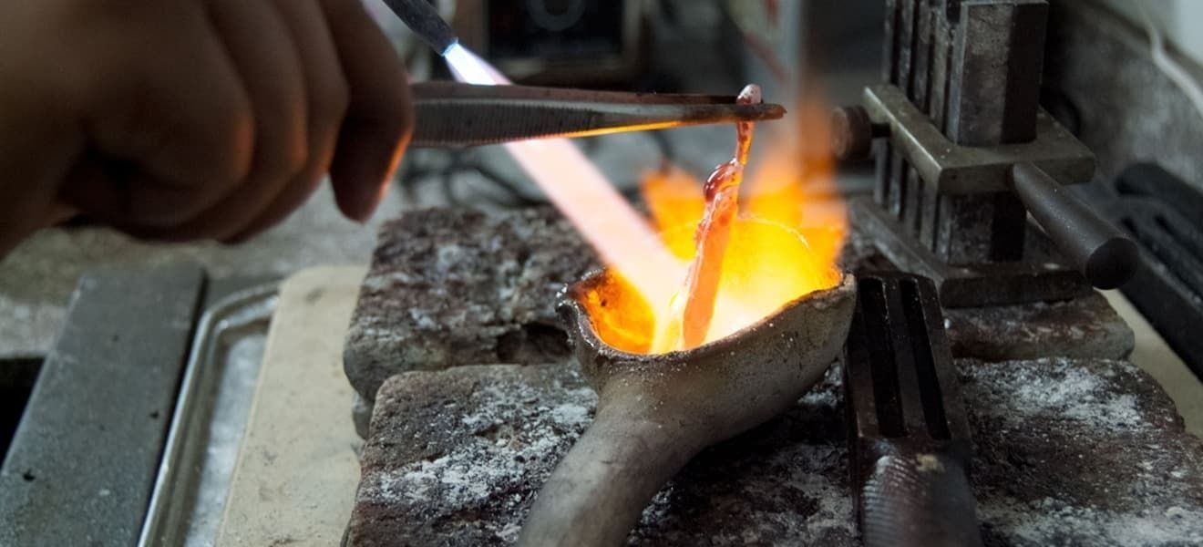 Una persona está fundiendo un trozo de metal en un horno.