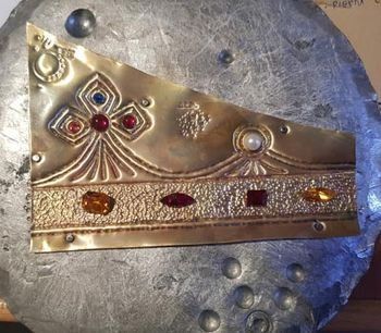 Una corona de oro reposa sobre una placa de plata.