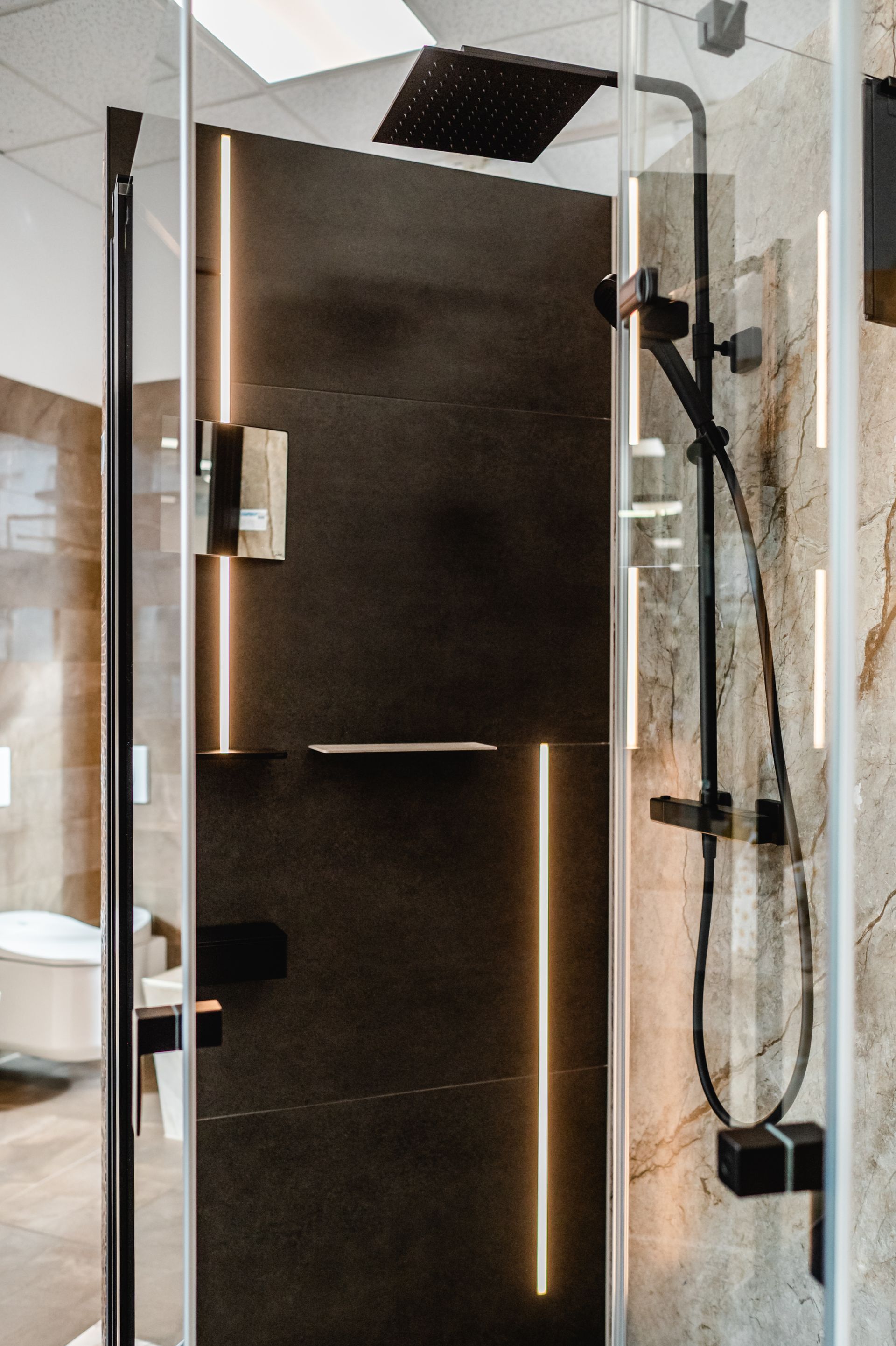 Moderne Dusche in Schwarz und Stein mit LED-Leuchten, Glastür und Regenduschkopf.