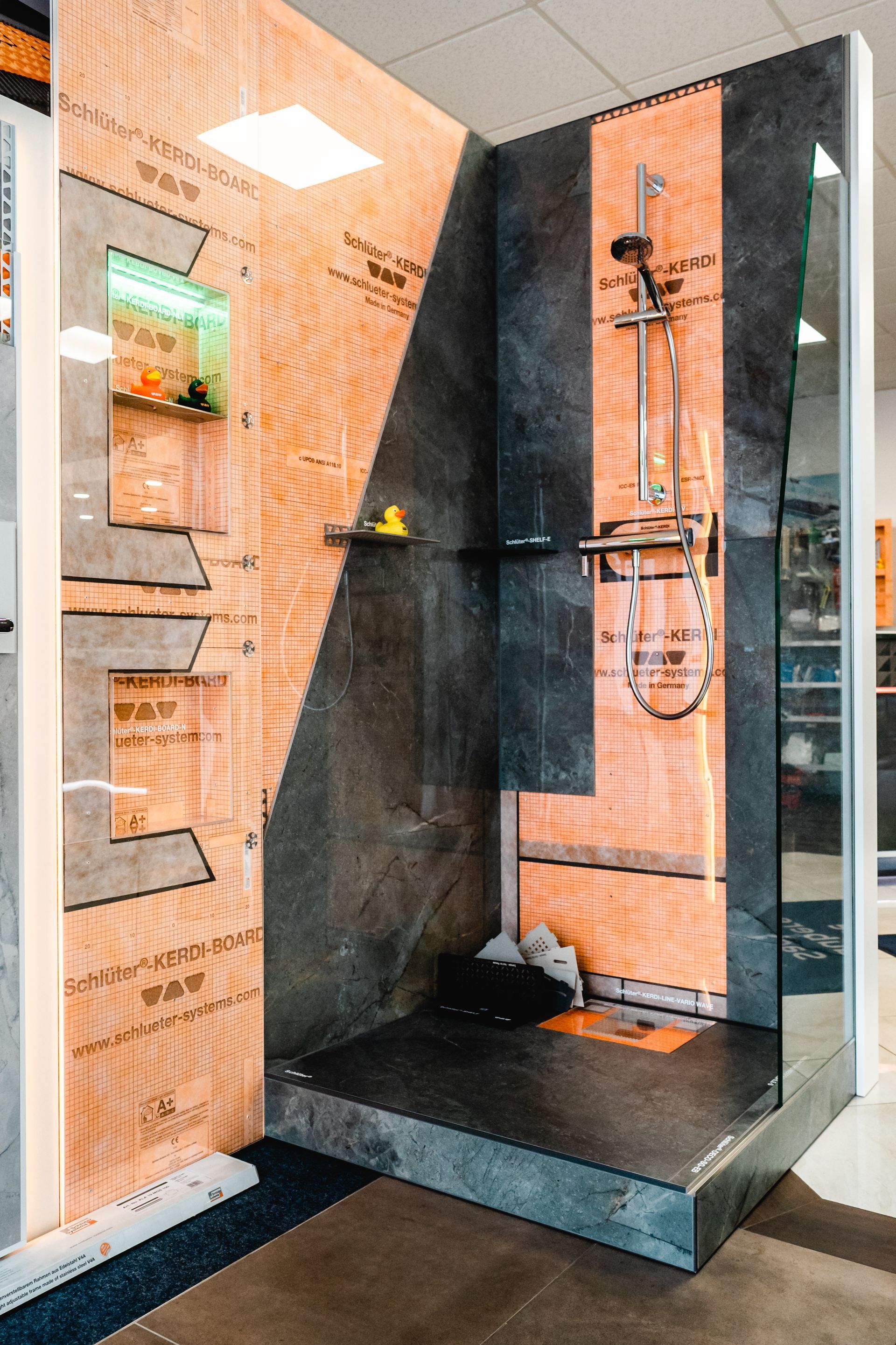 Duschkabinen-Display: Braun, Schwarz und Glas. Duschkopf, Regale und detaillierte Wandschichten.