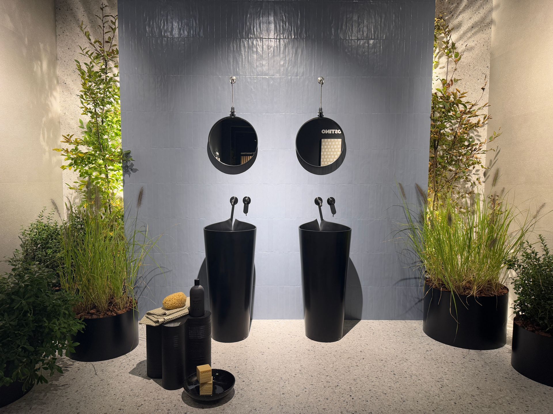Elegante graue Fliesenoptik im Hintergrund von Waschbecken und Pflanzen.