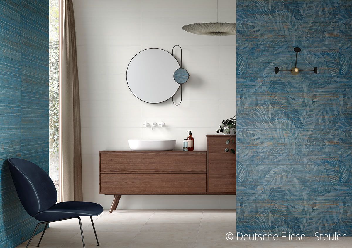 Modernes Badezimmer mit blau gemusterten Wänden, Holzwaschtisch und rundem Spiegel.