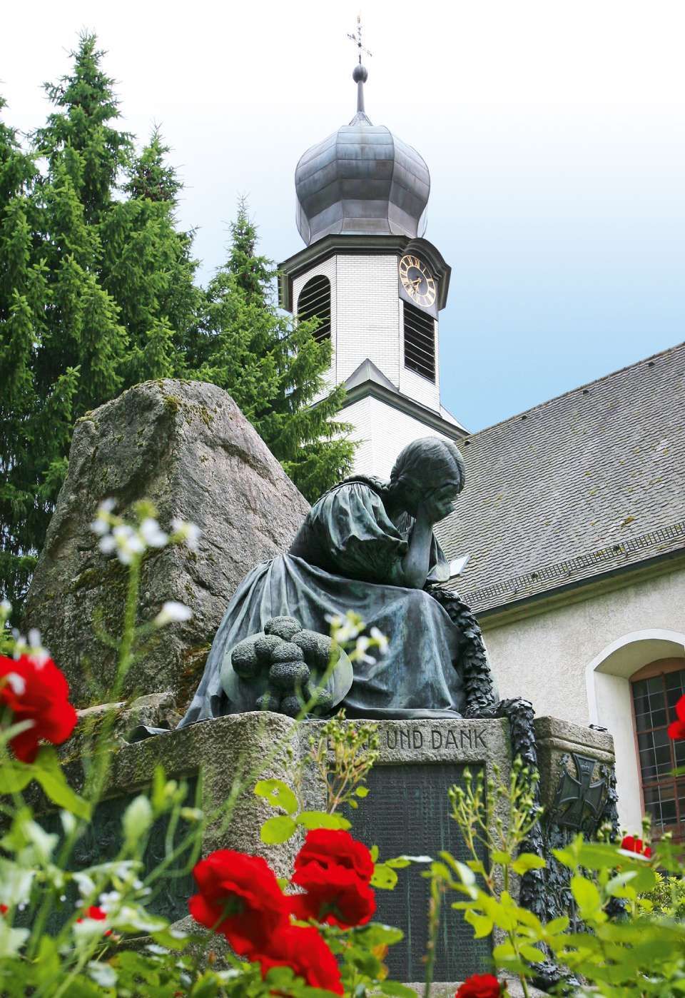 In einer Kapelle sind Kerzen, Blumen und eine Urne für eine Gedenkfeier aufgestellt. Darüber hängt ein Holzkreuz.