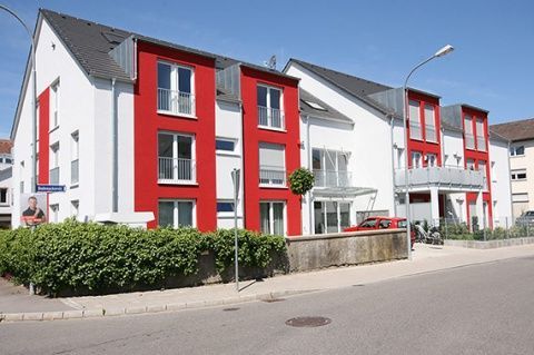 Mehrstöckiges Gebäude mit weißen Wänden, roten Akzenten und Blick auf die Straße.