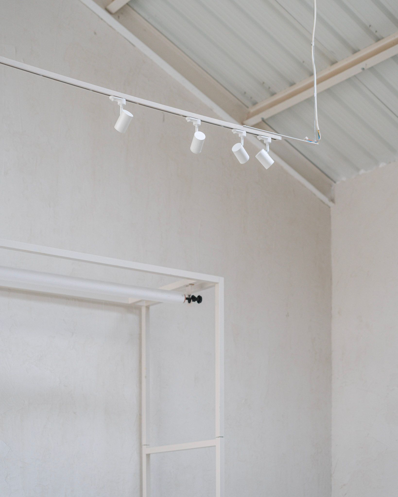 Interior blanco con iluminación de riel y una luminaria fluorescente larga y rectangular.