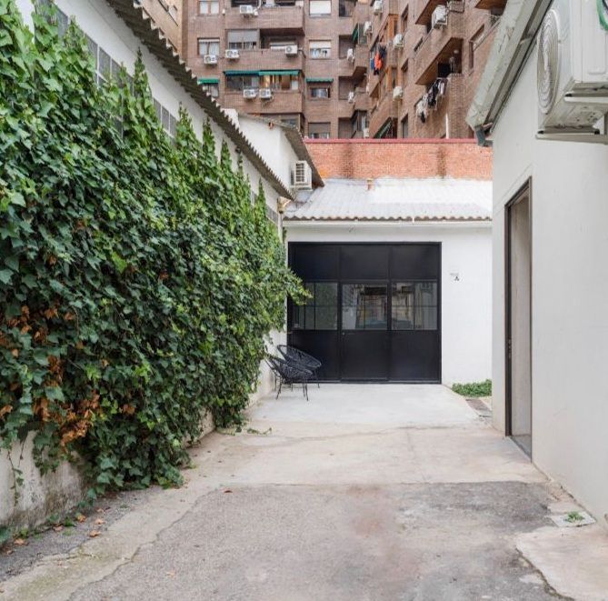 Habitación vacía, de paredes blancas, con suelo de hormigón y techo inclinado. La luz natural entra a raudales.