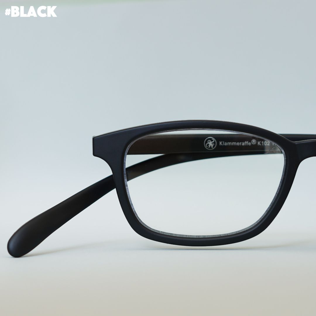 Schwarze Korrektionsbrille auf grauem Hintergrund.