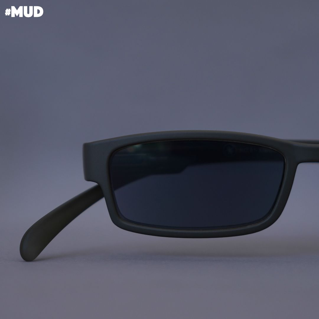 Eine Schlamm farbene Lesesonnenbrille auf grauem Hintergrund.