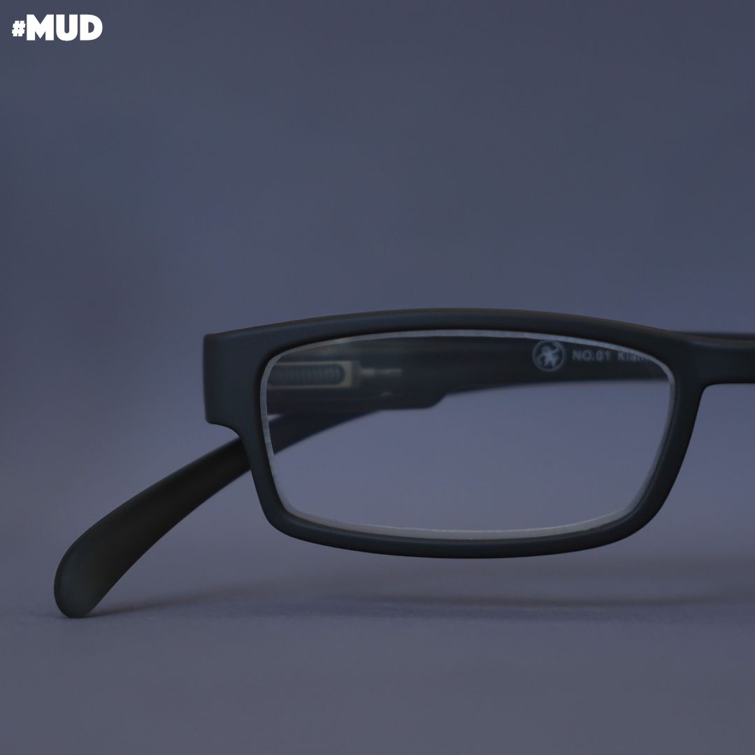 Eine Schlamm farbene Lesebrille auf grauem Hintergrund.