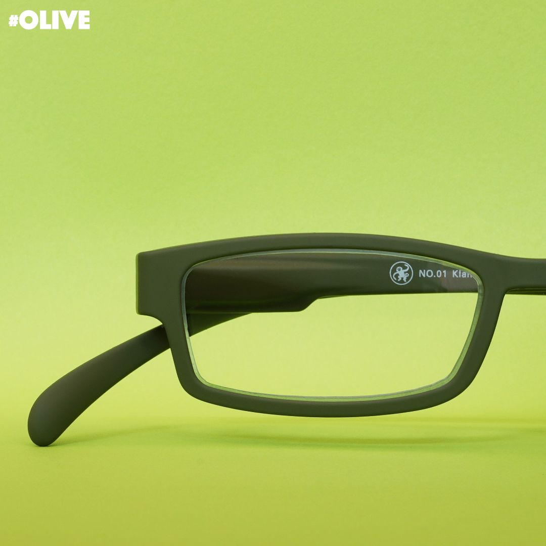 Eine olive farbene Lesebrille auf grünem Hintergrund.