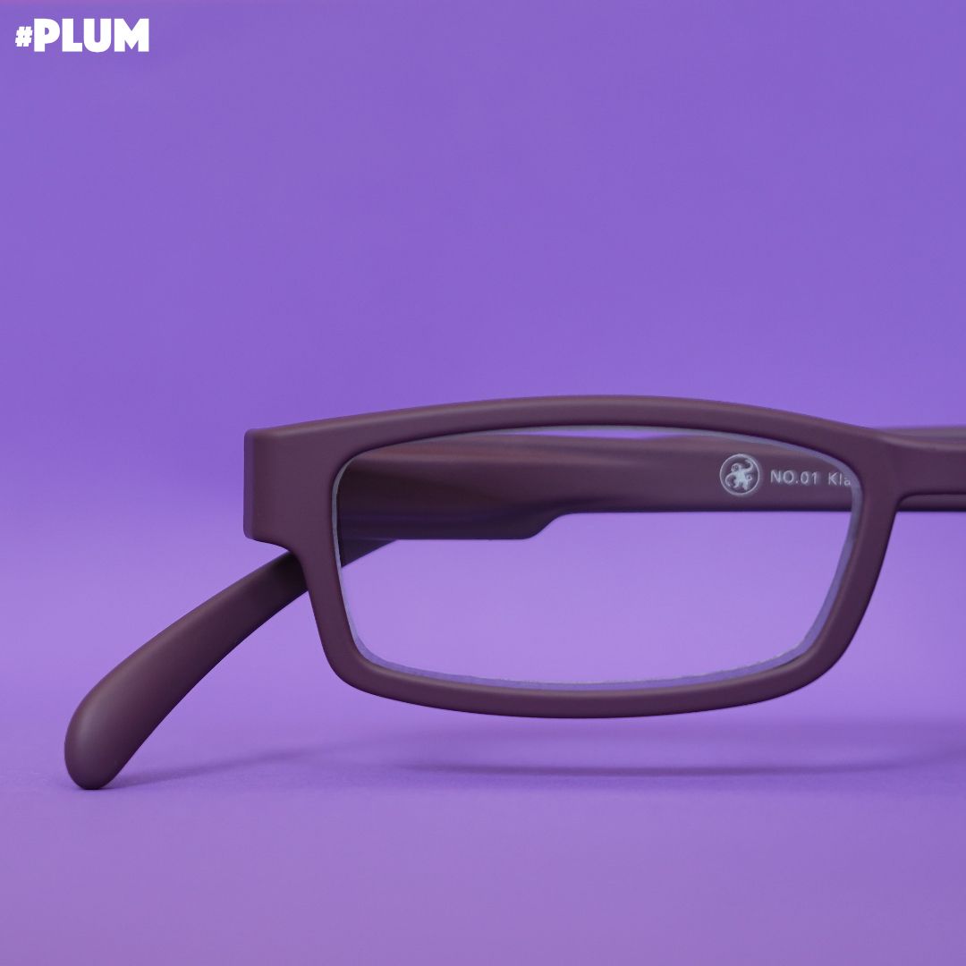 Eine pflaumen farbene Lesebrille auf lilanem Hintergrund.