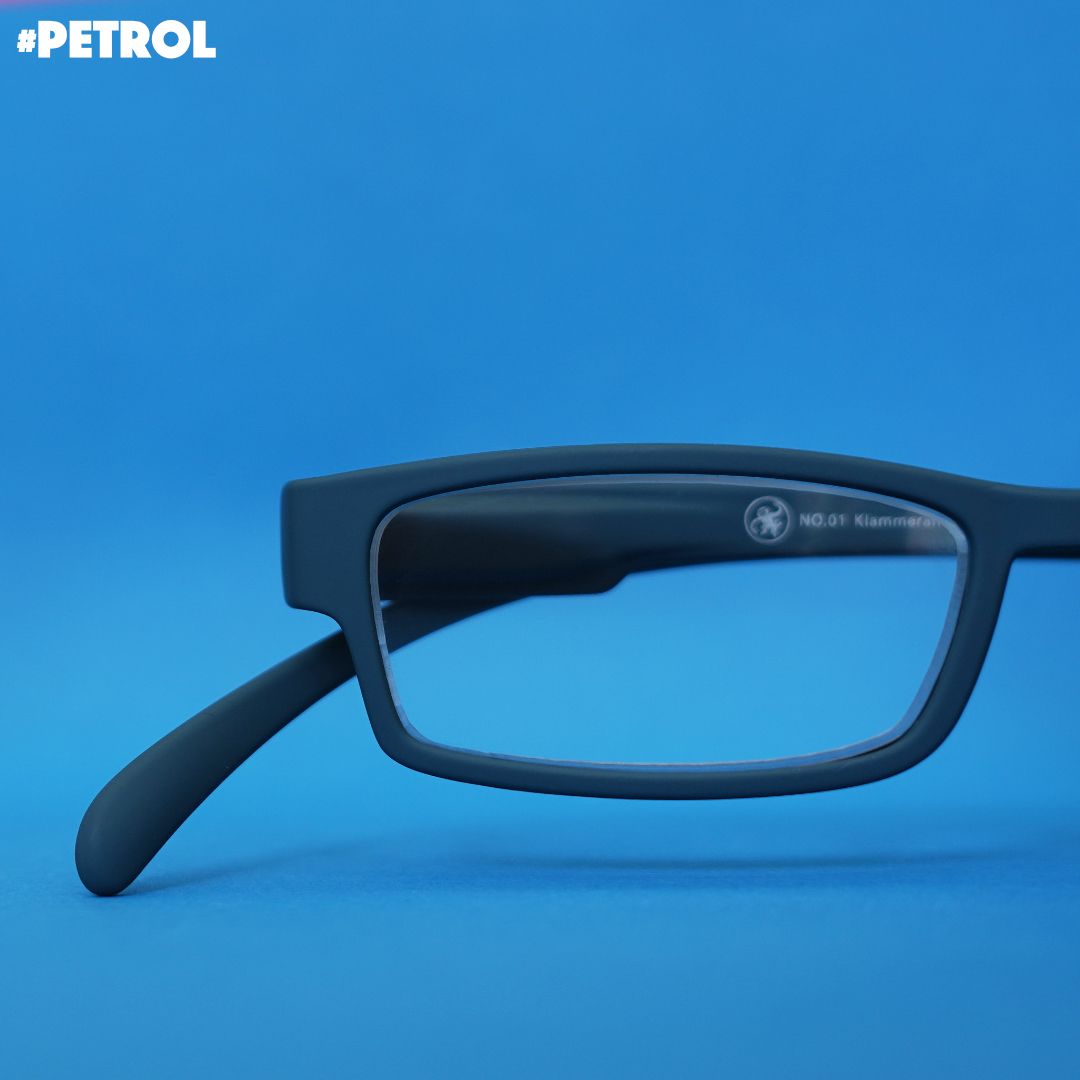 Eine petrol farbene Lesebrille auf blauem Hintergrund.