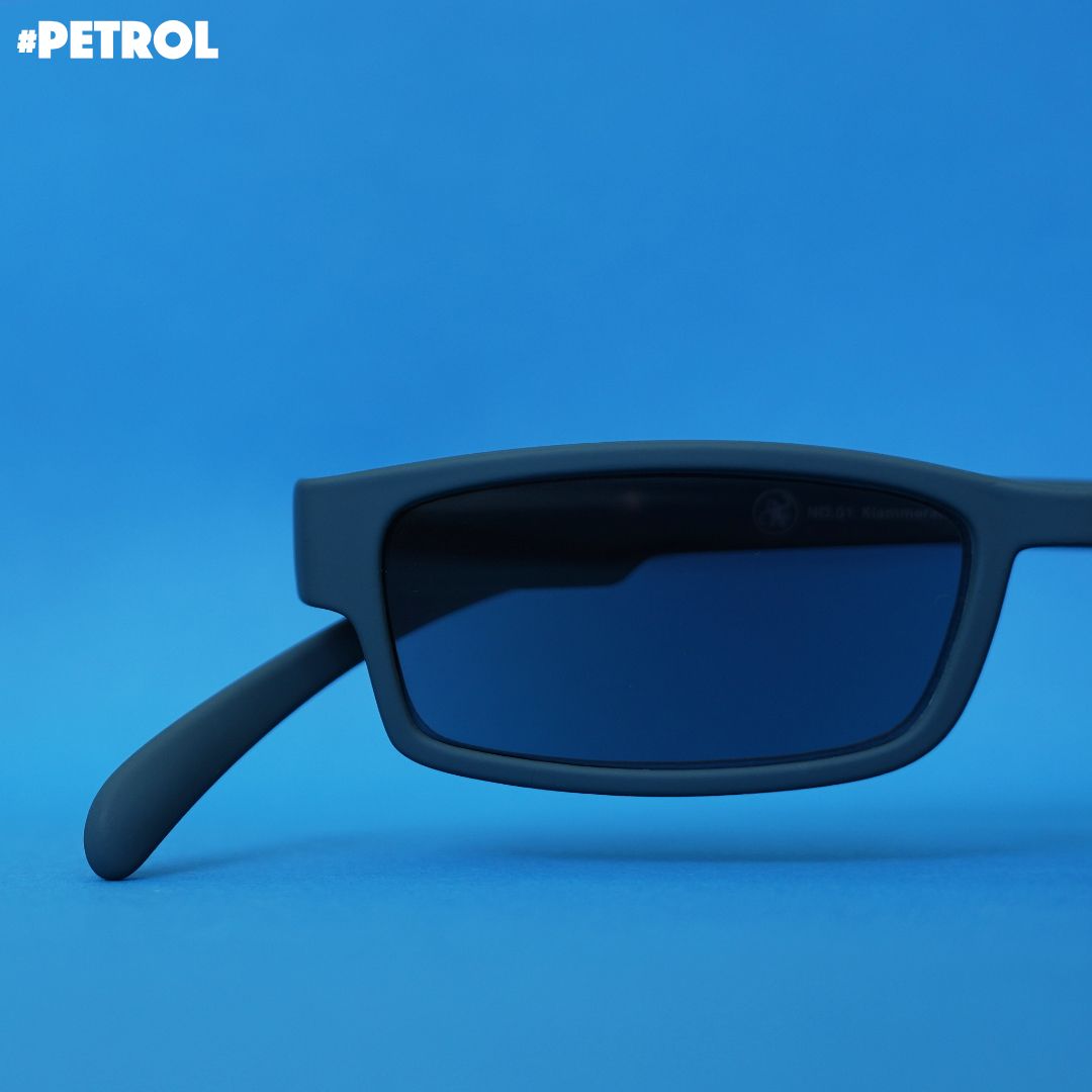 Eine petrol farbene Sonnenlesebrille auf blauem Hintergrund