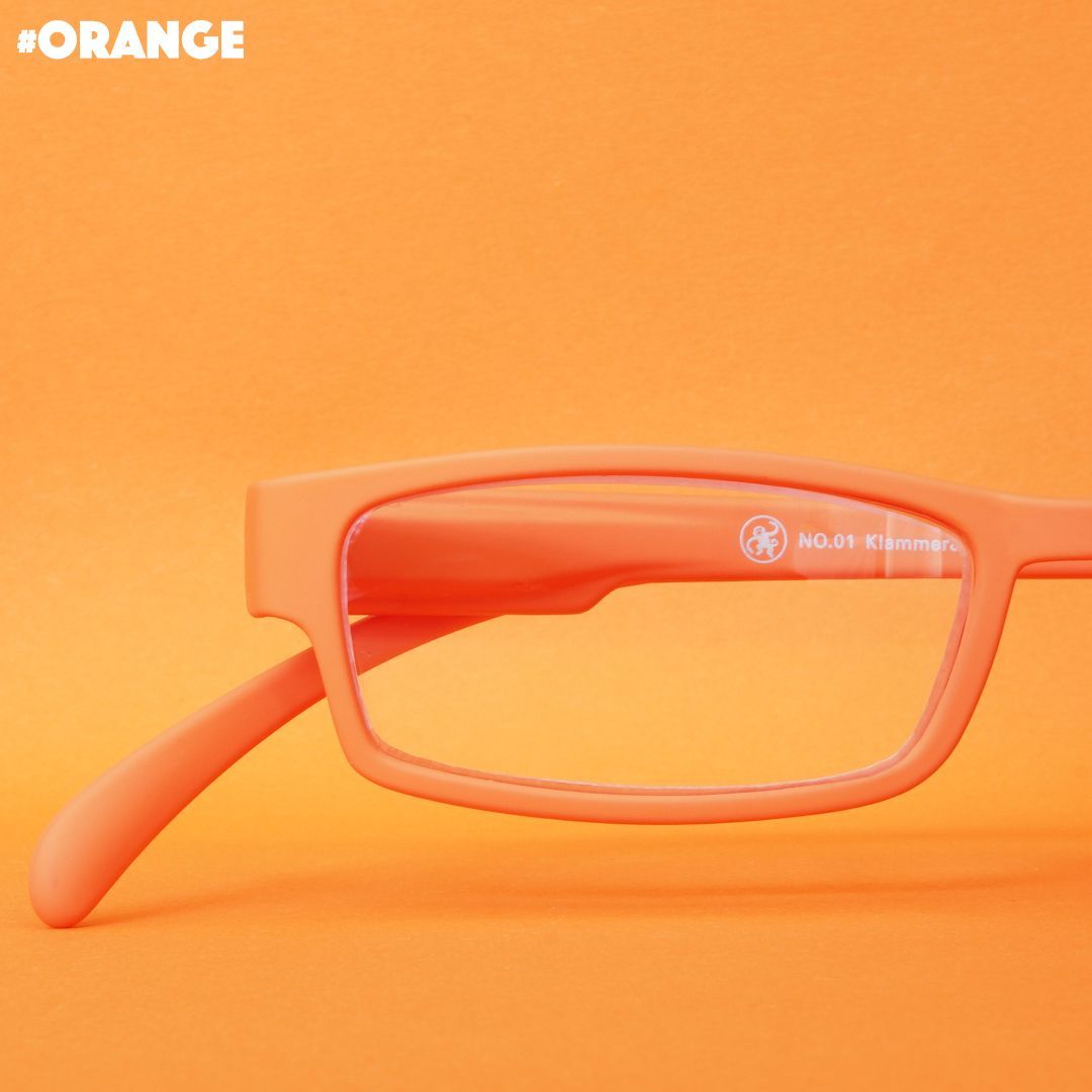 Eine orange farbene Lesebrille auf orangenem Hintergrund.