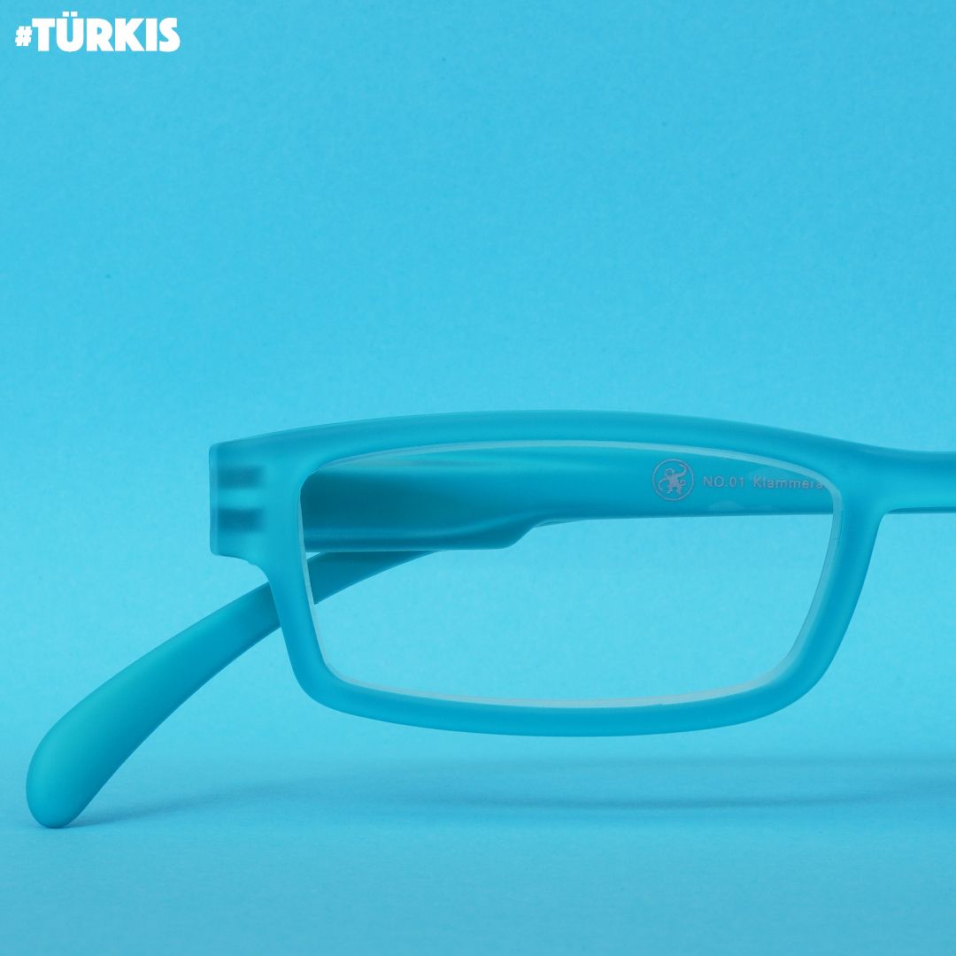 Eine türkise Lesebrille auf türkisem Hintergrund.