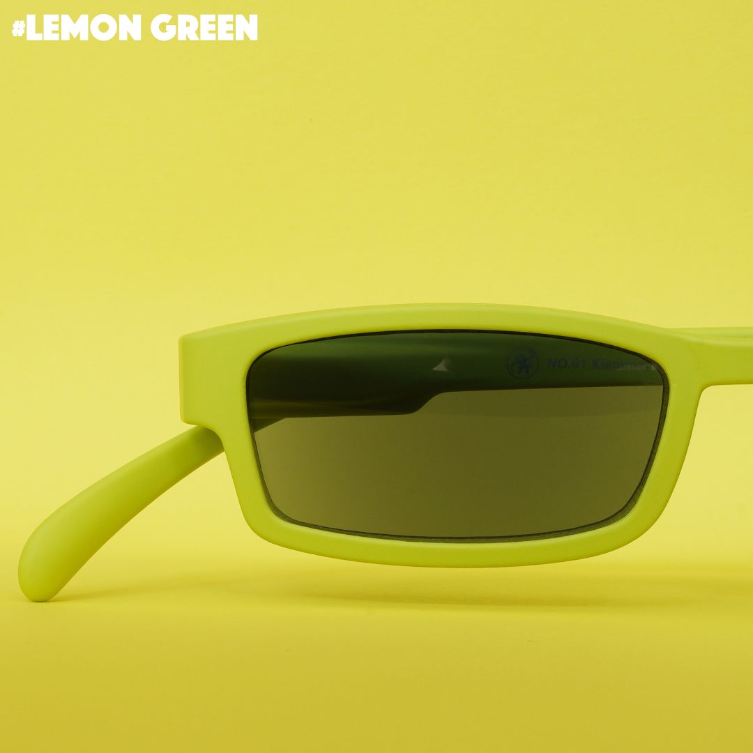Eine Limonen farbene Sonnenlesebrille auf hell grünem Hintergrund