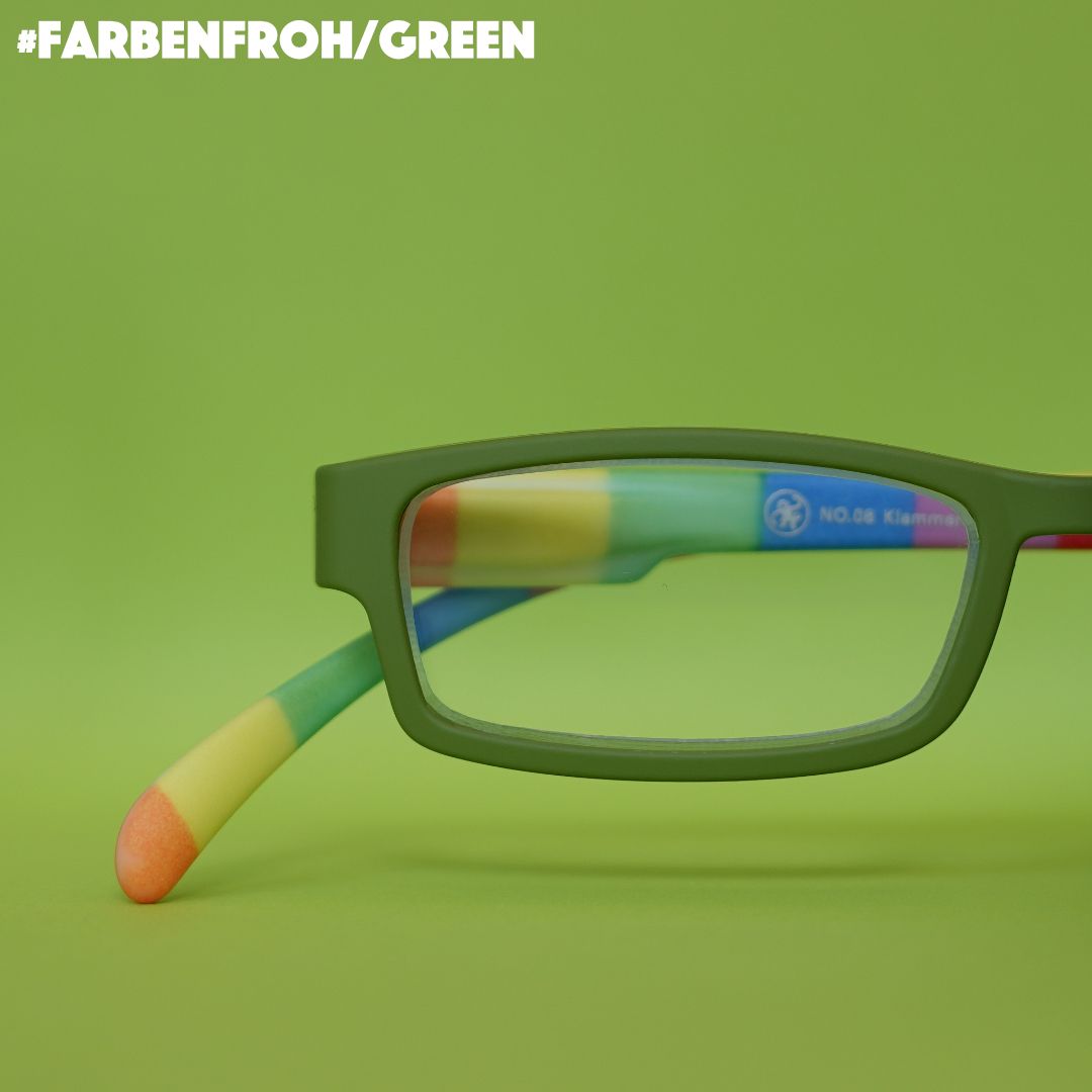 Eine grüne Lesebrille mit Bügeln im  gestreiften bunten Look auf grünem Hintergrund.