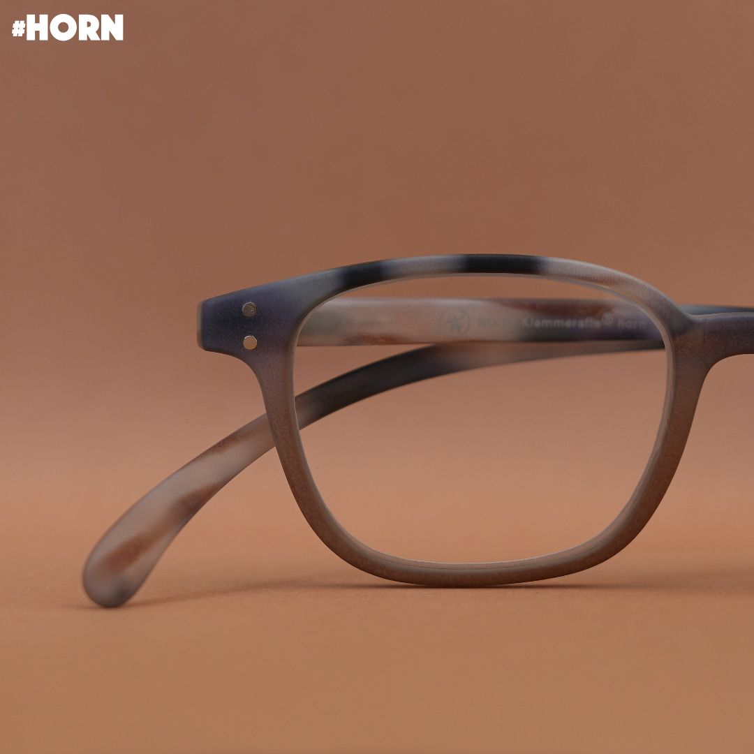 Eine Brille im Horn Style auf braunem Untergrund.