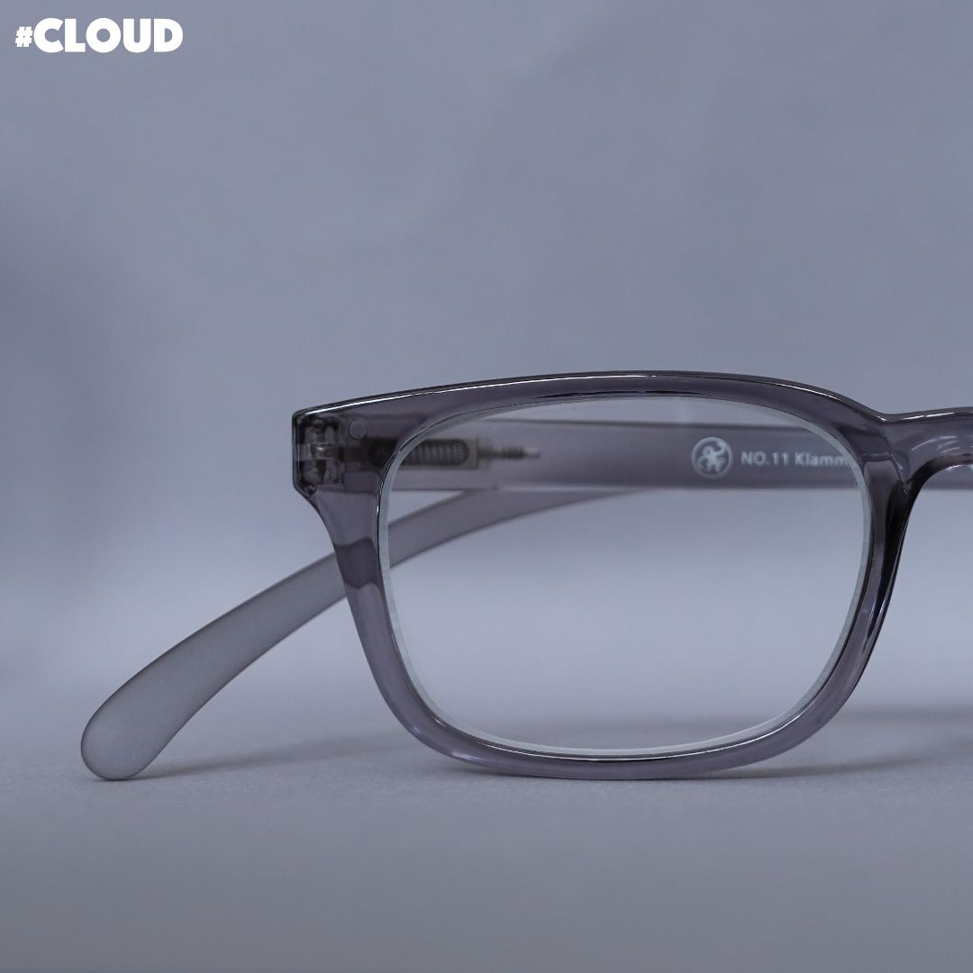 Eine grau transparente Lesebrille auf grauem Hintergrund.